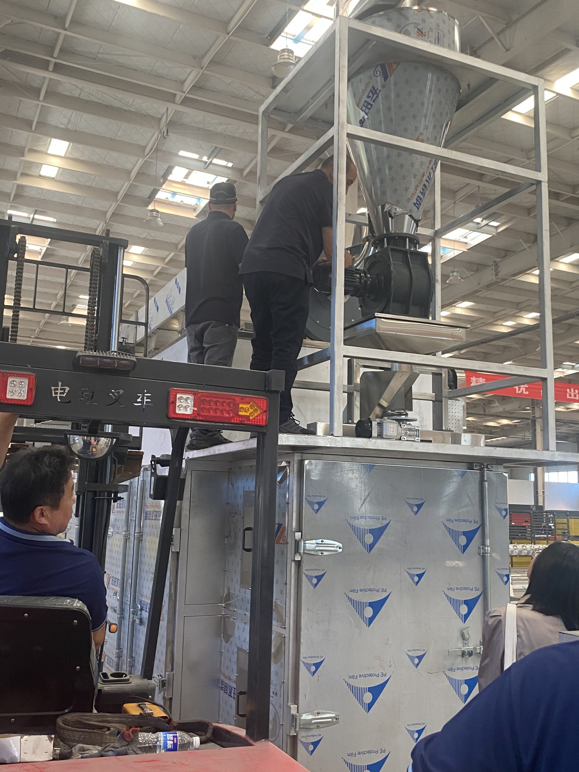 Visitors inspect equipment feeding and processing structure at ZEKO factory
